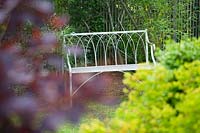 Caervallack, Cornwall, UK. ( McClary/Robinson ) Artists garden in summer, metal bench seen through foliage