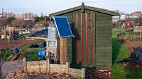Garden shed on allotment with solar panel to power rabbit proof fence