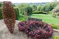 Derry Watkins Garden at Special Plants, Bath, UK with modern metal sculptural pot, 'Vessel' by David Mayne