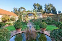 East Ruston Old Vicarage Gardens, Norfolk, Winter ( Alan Gray and Graham Robeson ). pond in the glasshouse garden with topiary pots