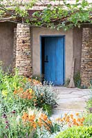 blue door of the grass-roofed hut in the  Sentebale - Hope in Vulnerability garden. RHS Chelsea Flower Show, 2015