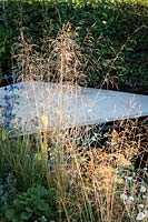 Hampton Court Flower Show, 2017. 'Watch this Space' garden, des. Andy Sturgeon. Backlit Deschampsia in small patio garden