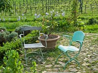 Parterre garden with chairs next to small circular pond at Locanda Casanuova, Tuscany, Italy