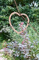 Little Ash Garden, Fenny Bridge, Devon. Autumn garden. Metal heart shaped sculpture
