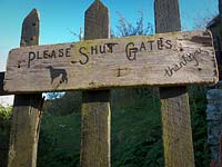 'Please shut the gate' hand written sign on wooden gate
