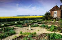 private garden Sussex gravel paths with bird bath focal point in Spring gazebo view of field of oil seed rape