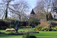 Rymans Sussex walled garden with lawn in Spring with island beds and Armillary sphere