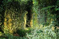 Private garden Surrey classical statue beside walled garden gate.