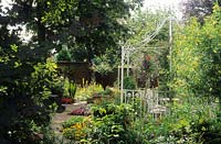 White painted gazebo with table and chairs Hanging baskets Snap Dragons Antirrhinum seating summer house pavilion August