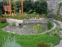 The Harmonious Garden of Life garden with a water feature that incorporates a dry stone wall surrounded by a gravel path with the soft backdrop of Stipa tenuissima- Designer: Laurélie de la Salle - Sponsor: Mr Robert and Mrs Sue Cawthorn Margheriti Piante, Italy