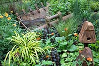 Walker's Forgotten Quarry Garden, metal digger bucket used to make an ingenious small pond, bordered with Geum 'Totally Tangerine' - Design: Graham Bodle. Sponsor: Walkers Nurseries
