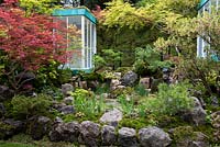 The Green Switch Garden. A Japanese garden with a Sedum roof structure overlooking waterfalls tumbling into a pond, surrounded by Acers, pines, ferns and mosses. Awarded an RHS Gold Medal. Design: Kazuyuki Ishihara. Sponsor: G Lion.