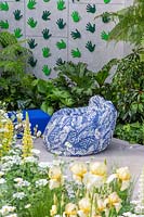 Patterned bean bag in modern garden, surrounded by lush planting. The Greenfingers Charity Garden. Designed by Kate Gould Gardens, sponsored by Greenfingers Charity, RHS Chelsea Flower Show, 2019.
