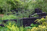 The M and G Garden, RHS Chelsea Flower Show 2019, Design: Andy Sturgeon, Sponsor: M and G - Woodland with blackened timber sculptures by Johnny Woodford. Awarded an RHS Gold Medal. Chelsea Flower Show 2019