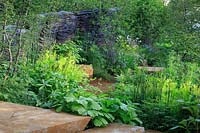 The M and G Garden Designer:  Andy Sturgeon  - Sponsor: M and G Investments Gold medal, Best in Show.
Overview of garden with green plantings and stone steps and charred wooden sculpture