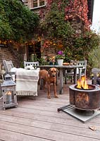 Garden table, chairs and fire basket on garden terrace set up for evening entertaining, Le Mas de BÃ©ty, France
