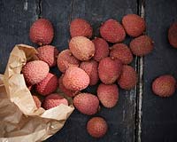 Litchi chinensis, Lychee spilling out of brown paper bag. 