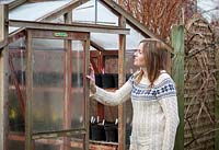 Opening a greenhouse door for ventilation in winter