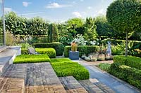 Clipped box hedges, topiary and a patio in a contemporary garden.