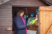 Woman tidying chemicals and sprays a shed.
