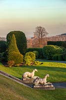 A view of the lawns and formal topiary gardens at Brodsworth Hall, Yorkshire at dusk.
