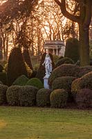 A garden statue among clipped topiary hedging at dusk, Brodsworth Hall, Yorkshire. 