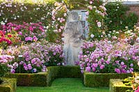 Rosa - 'David Austin roses in a formal setting with R. 'Harlow Carr' alongside sculpture and bed edged with clipped 
Buxus - box edging

in the