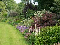 Herbaceous borders are well stocked with plants to add interest to the garden over a long period and the planting closely follows the contours of the lawn.