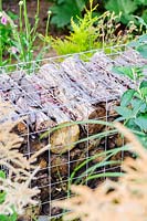 A log filled gabion used to create a low garden wall, Lower Treculliacks Farm, Falmouth, Cornwall, UK.