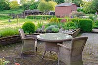 Garden table and chairs on garden terrace with view of the garden, Terstan, Stockbridge, Hants, UK. 
