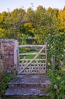 A view of a wooden chestnut gate with garden beyond. 