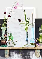 Still life on shelf with multiple vases and framed illustration. 