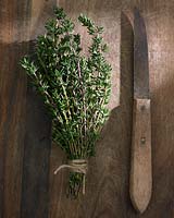 Rosmarinus officinalis and knife on wooden chopping board.
