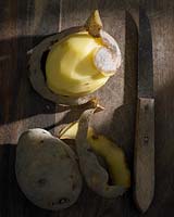 Solanum tuberosum 'Frieslander' - potato - and knife on wooden surface. 
