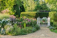 A view of an antique cast iron gateway and herbaceous border. 