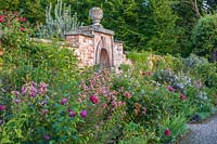 Kitchen walled garden Lilium speciosum 'Black Beauty' and Clematis viticella 'Emilia Plater' - Morton Hall Gardens, Worcestershire
