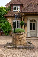Front of house with gravel terrace and old stone well, Surrey