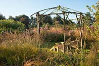 Rustic gazebo at Ellicar Gardens, Nottinghamshire with perennial borders