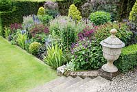 Herbaceous border with lawn stone steps and old stone urn, Scotland 