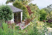 View of garden studio surrounded by flowering beds and borders. 