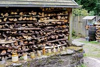 A covered log pile with a decorative line of vintage ceramic jars.  