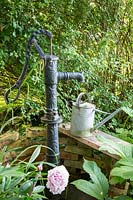 An old fashioned water well with metal watering can. 