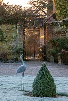 Cast iron gate with frosted metal bird sculpture and box topiary, West Sussex