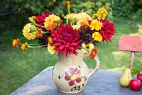Red dahlias with tagetes in old pottery jug