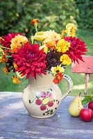 Red dahlias with tagetes in old pottery jug
