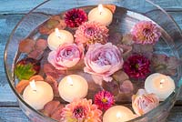 Floating flowers and candles in low glass bowl.