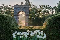 View over formal clipped hedging to stone archway at Arundel Castle in Sussex, UK. 