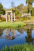 Island on lake is connected to rest of garden by a wooden footbridge at Cholmondeley Castle, Cheshire, UK. 
