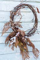 Dried vine wreath decorated with foraged fern leaves and dried seedheads.