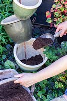 Filling ceramic pots with compost using a scoop